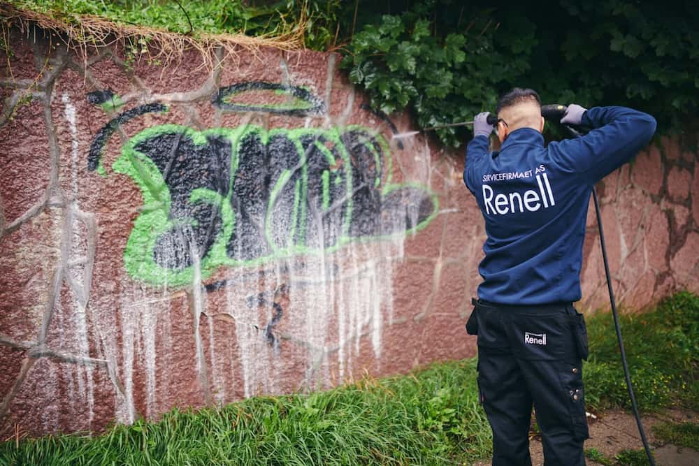 Renell-medarbejder fjerner grafitti fra mur